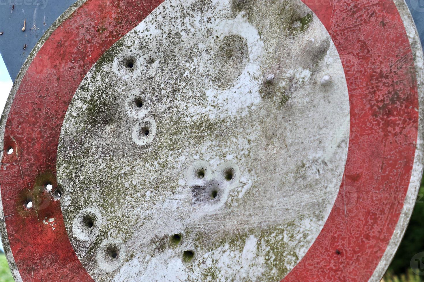 Detailed close up of bullet holes from gun shots in a traffic sign photo