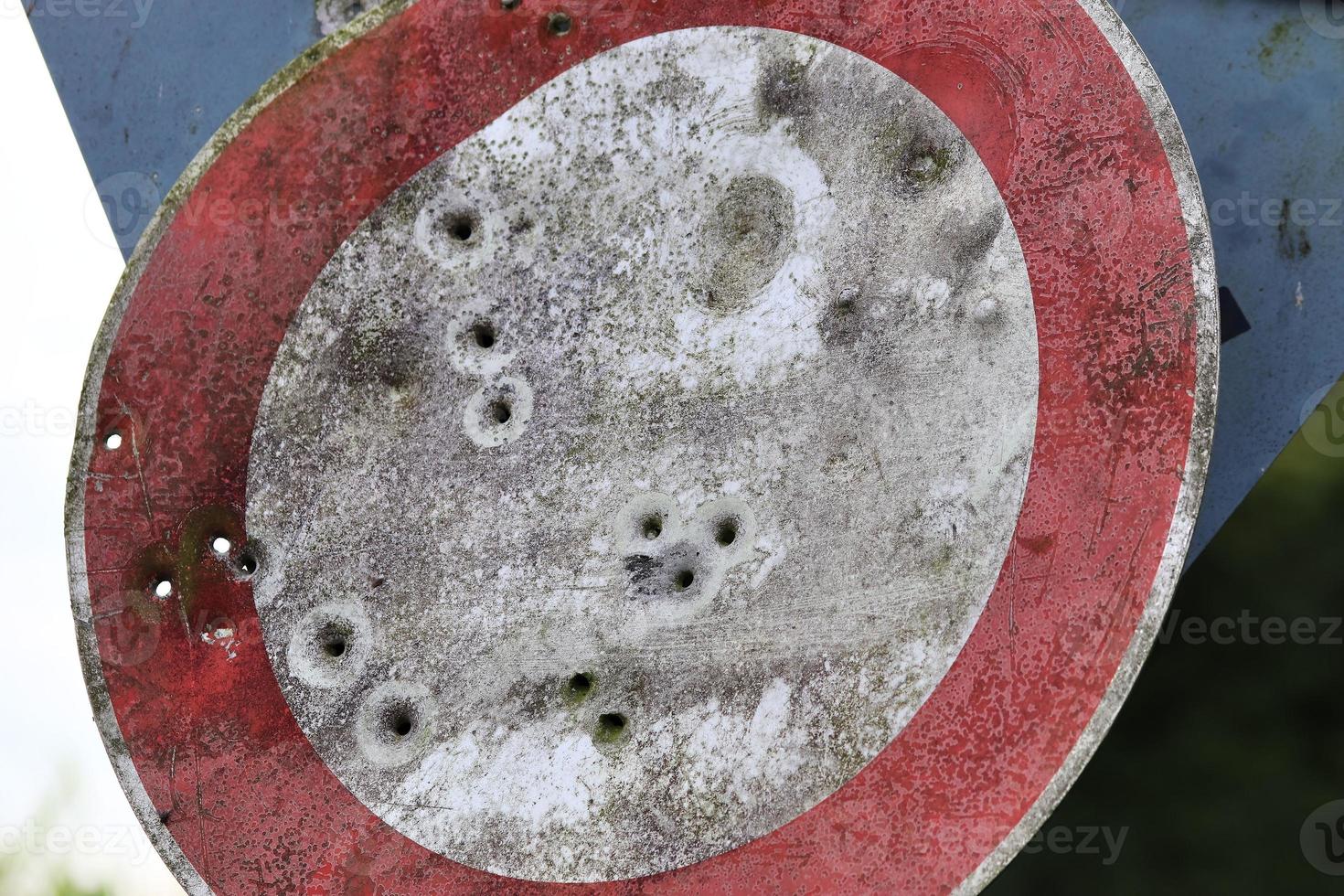 Detailed close up of bullet holes from gun shots in a traffic sign photo