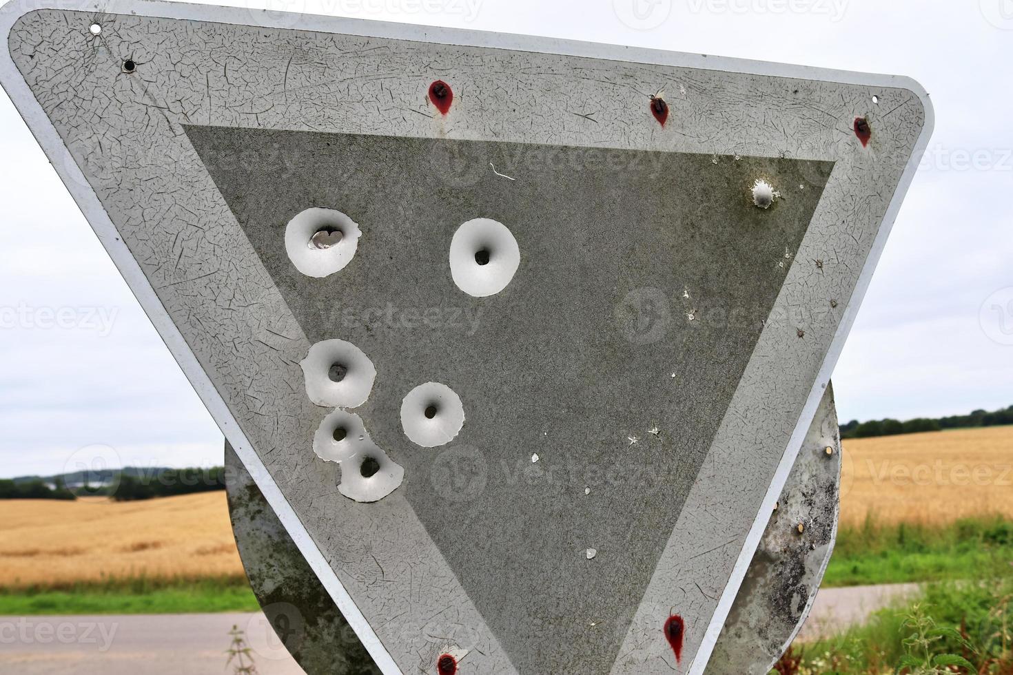 Detailed close up of bullet holes from gun shots in a traffic sign photo