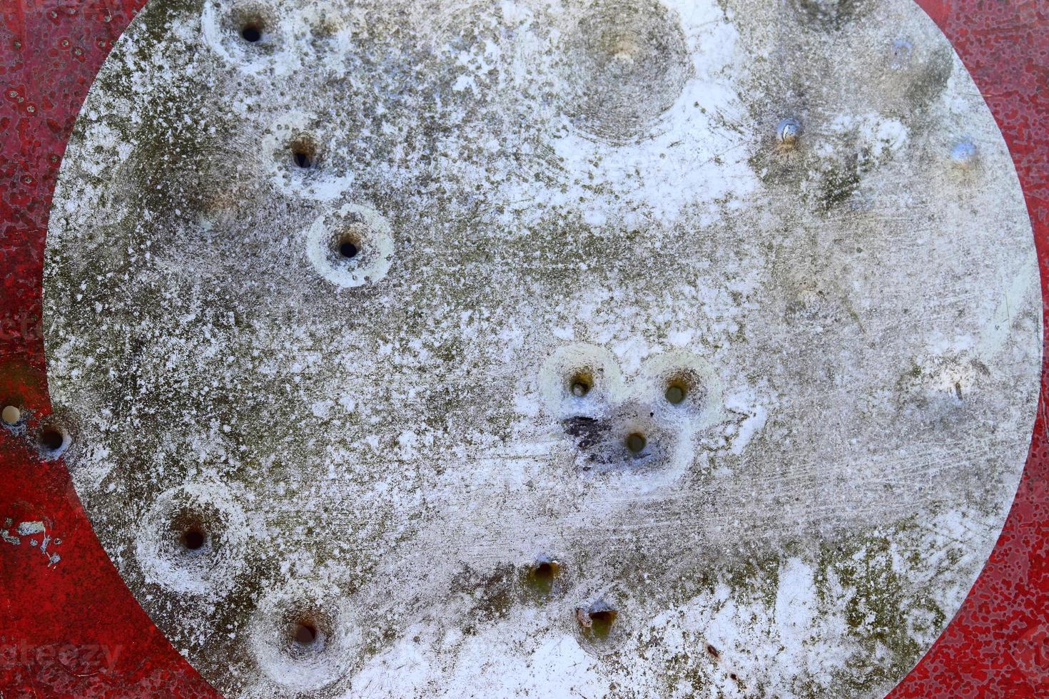 Detailed close up of bullet holes from gun shots in a traffic sign photo