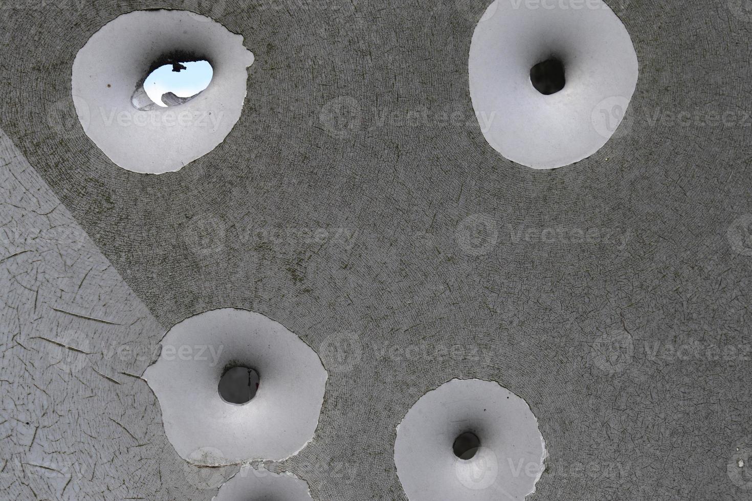 Detailed close up of bullet holes from gun shots in a traffic sign photo