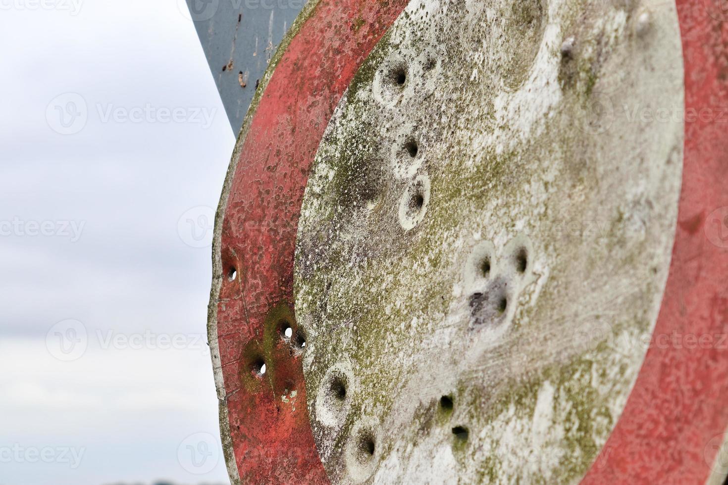 Detailed close up of bullet holes from gun shots in a traffic sign photo