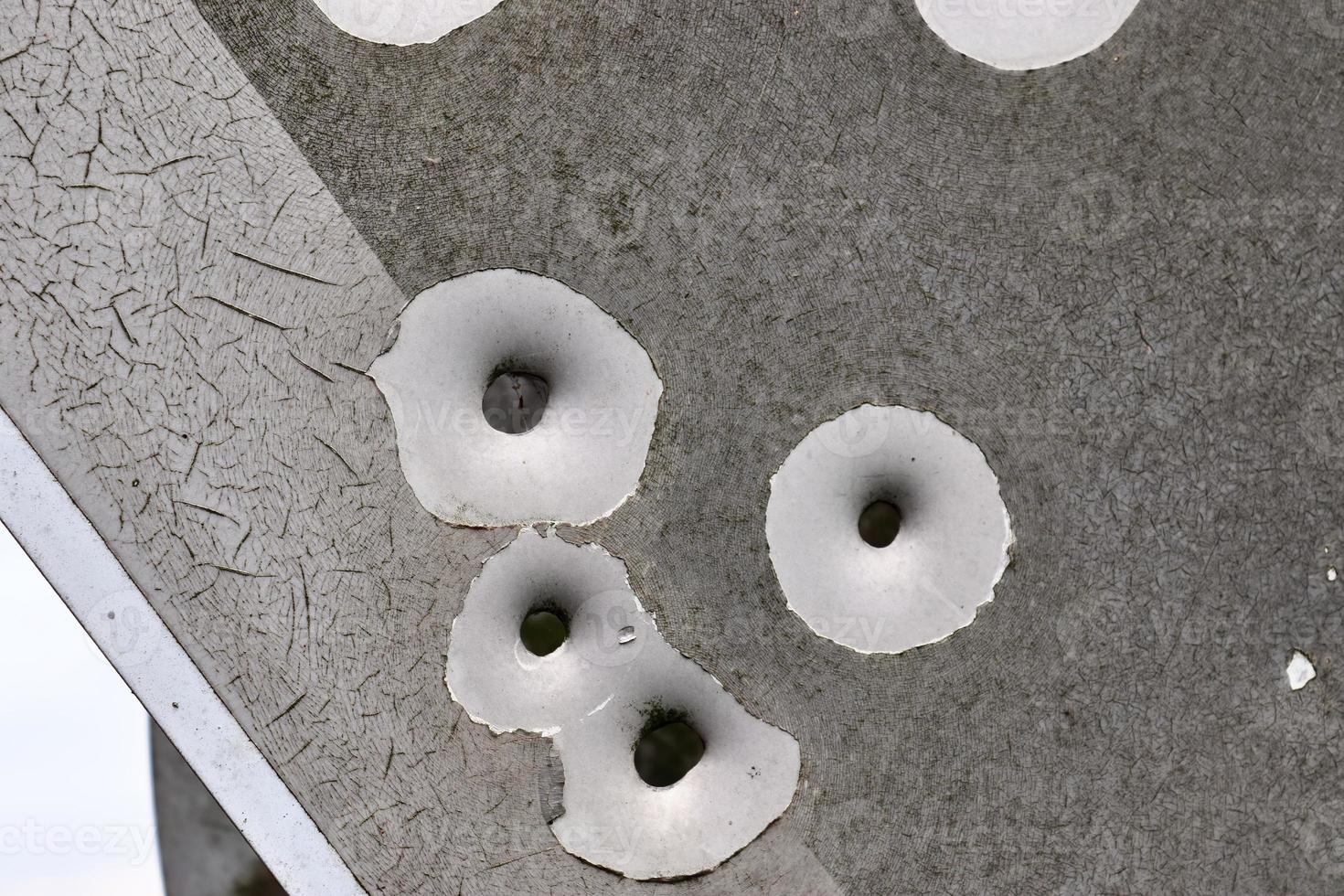 Detailed close up of bullet holes from gun shots in a traffic sign photo