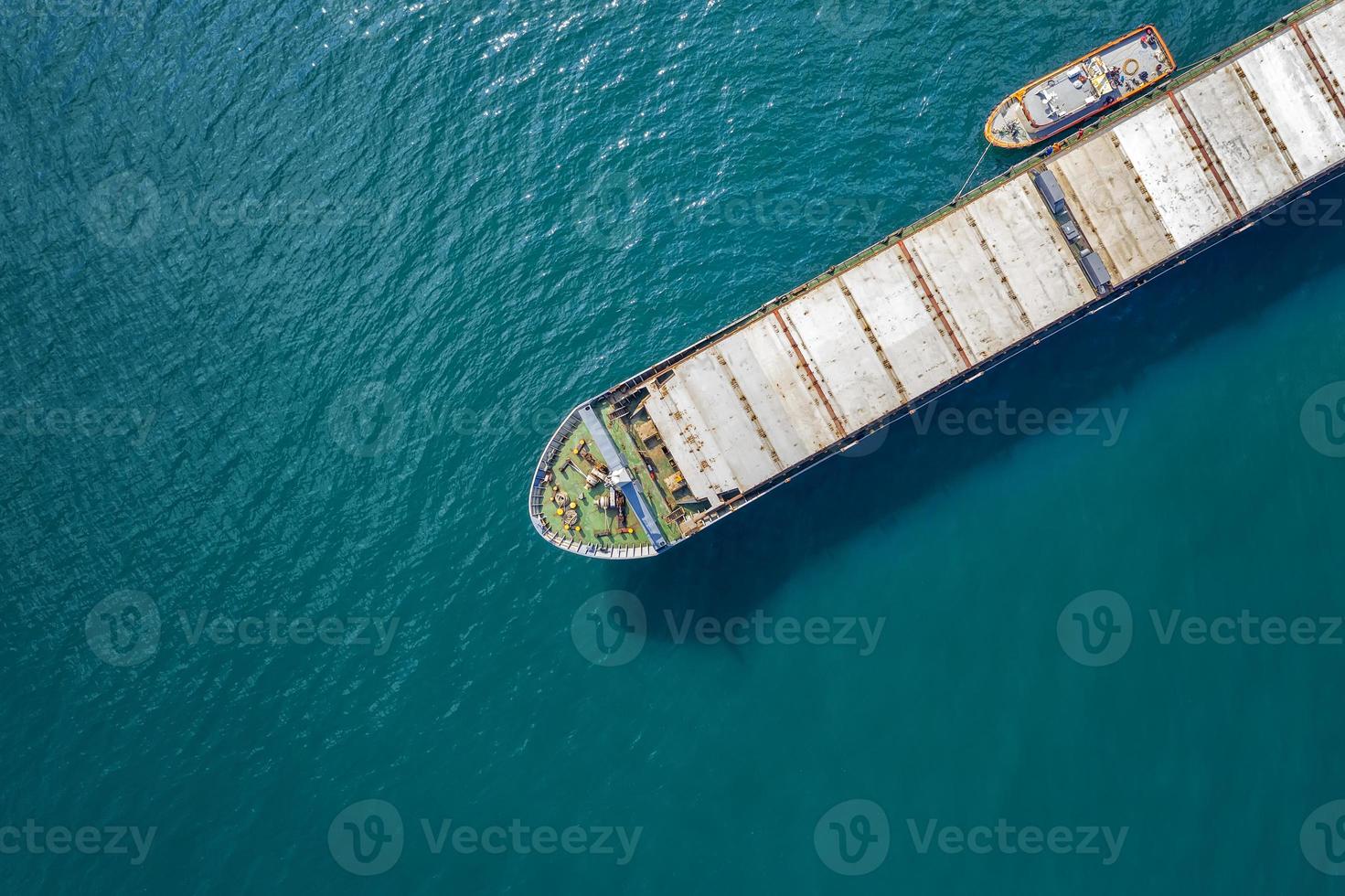 Aerial shot of a cargo ship approaching port with help of towing ship photo