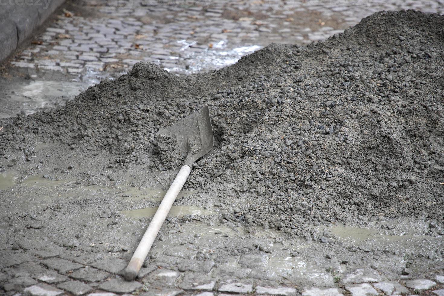 Hand mixing concrete mortar with shovel on construction site. photo