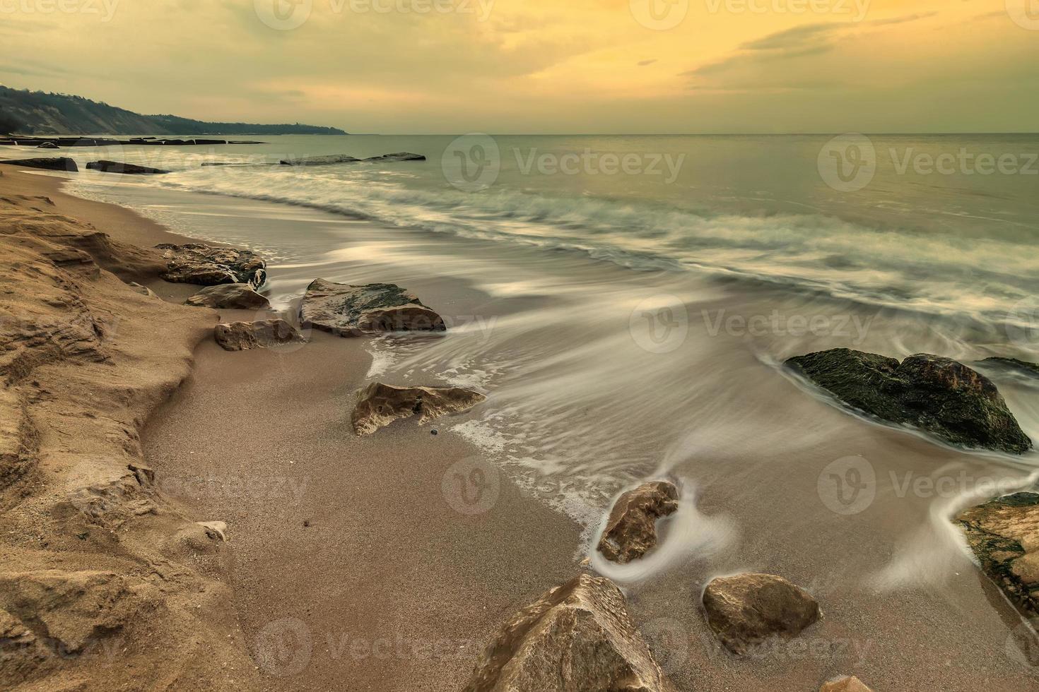 Beauty cloudy, long exposure seascape with waves flowing between rocks. photo
