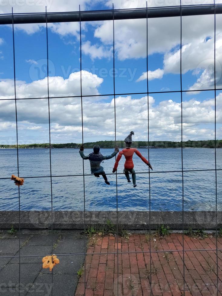 Two small wooden figures hanging in a construction fence in front of the baltic sea water in northern Germany. photo