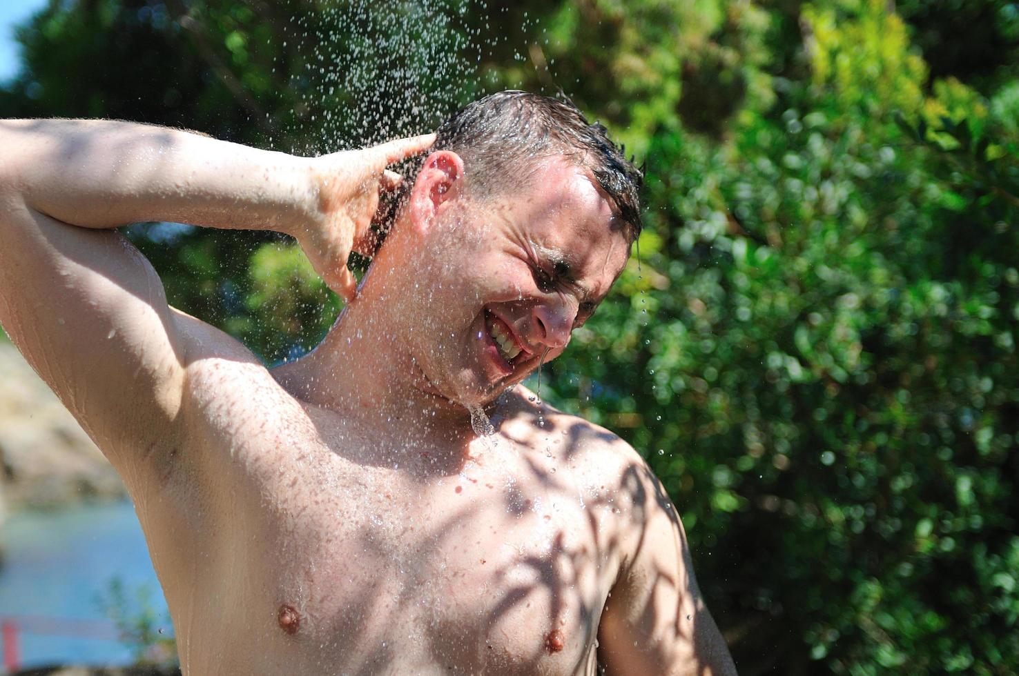young man relaxing under shower photo