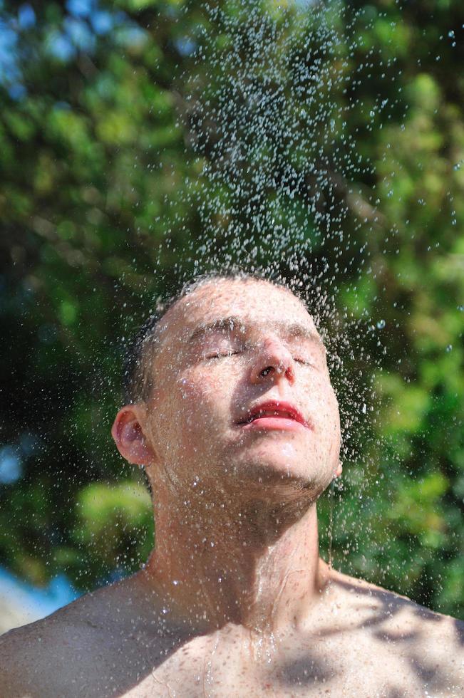 young man relaxing under shower photo