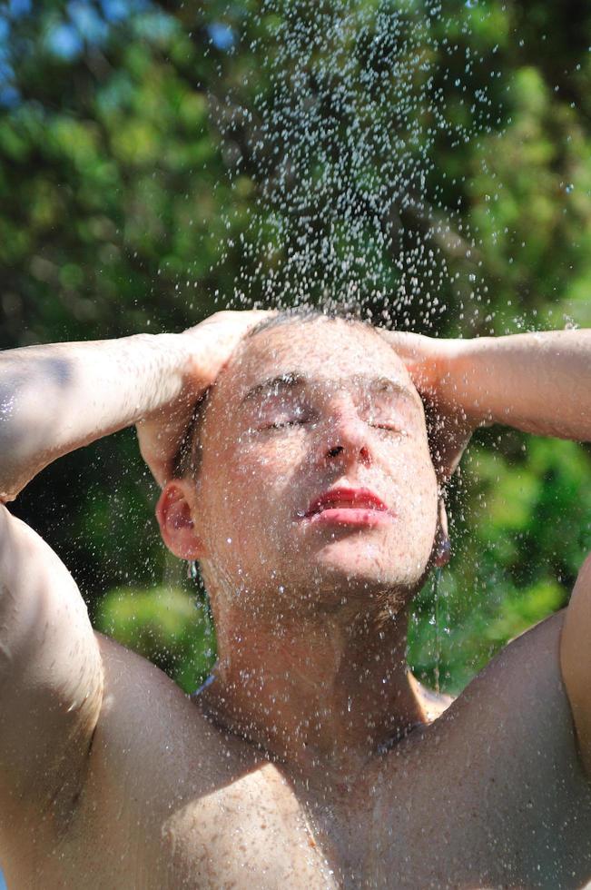 young man relaxing under shower photo