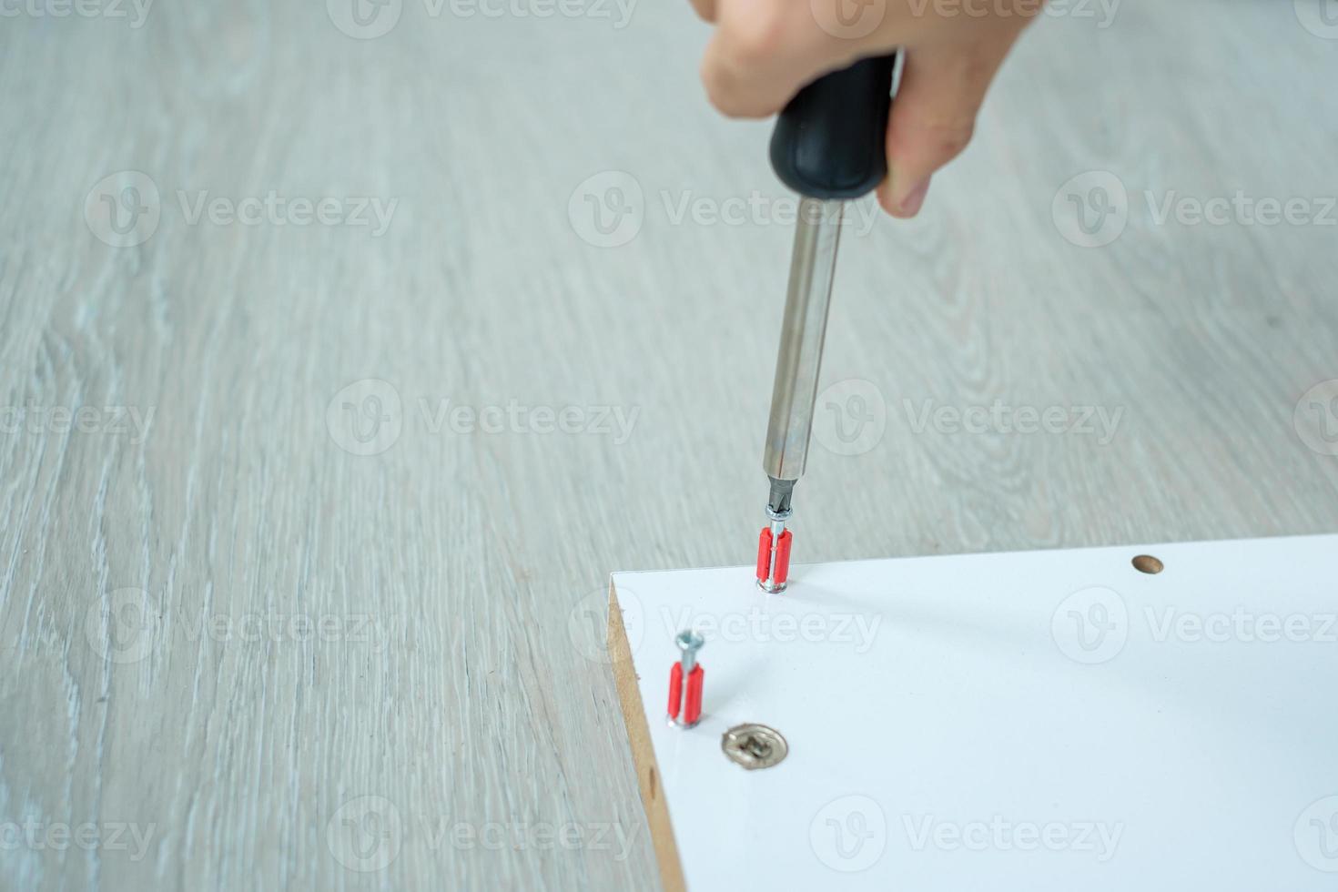 man using screwdriver assembling or repairing furniture at home. DIY, Renovation, repairing and development home or apartment concepts photo