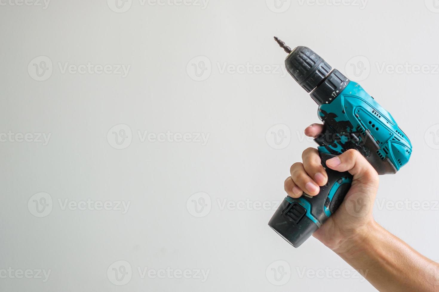 man hand holding cordless screwdriver with wall background, Carpenter working with electric screwdriver on the work photo