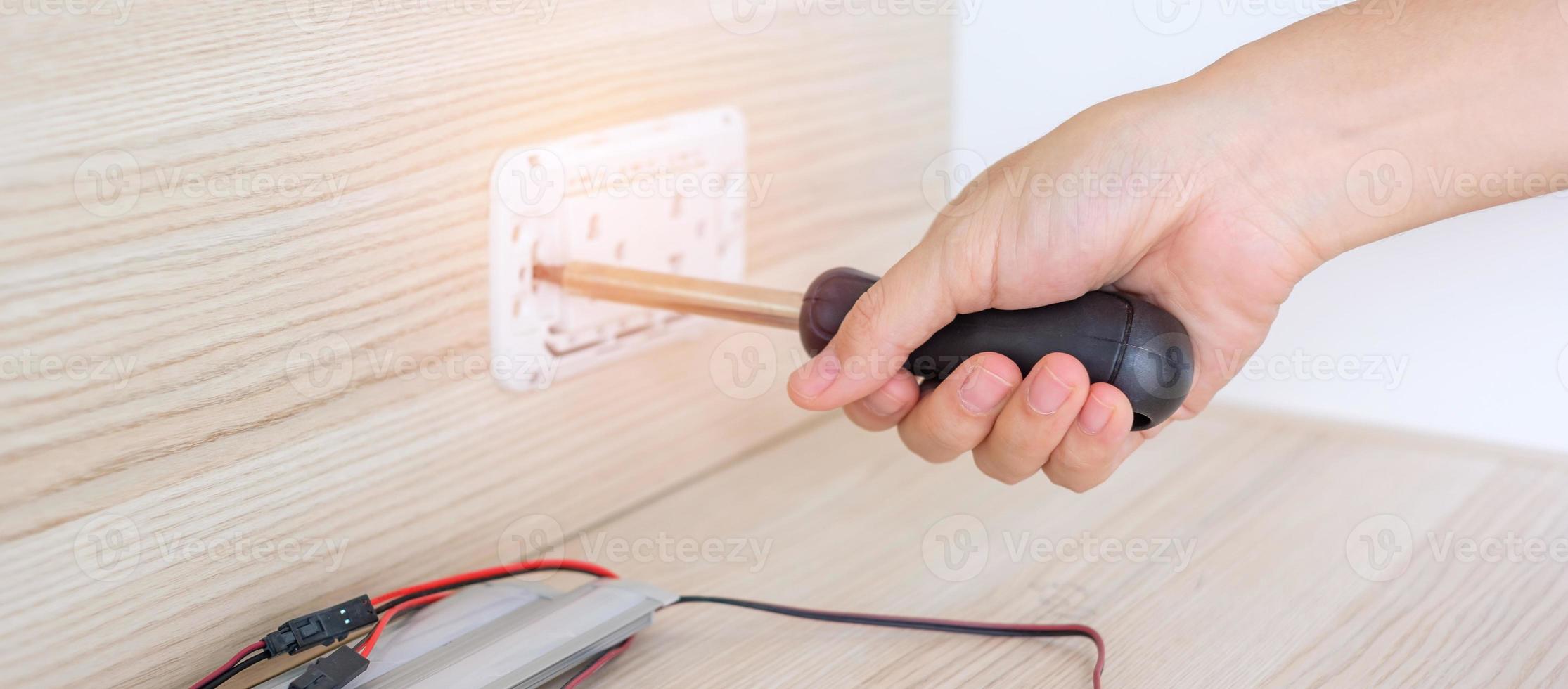 Man hand using screwdriver installing Wire cables for socket plug. Renovation, Repair, fixing and development of home and apartment concepts photo