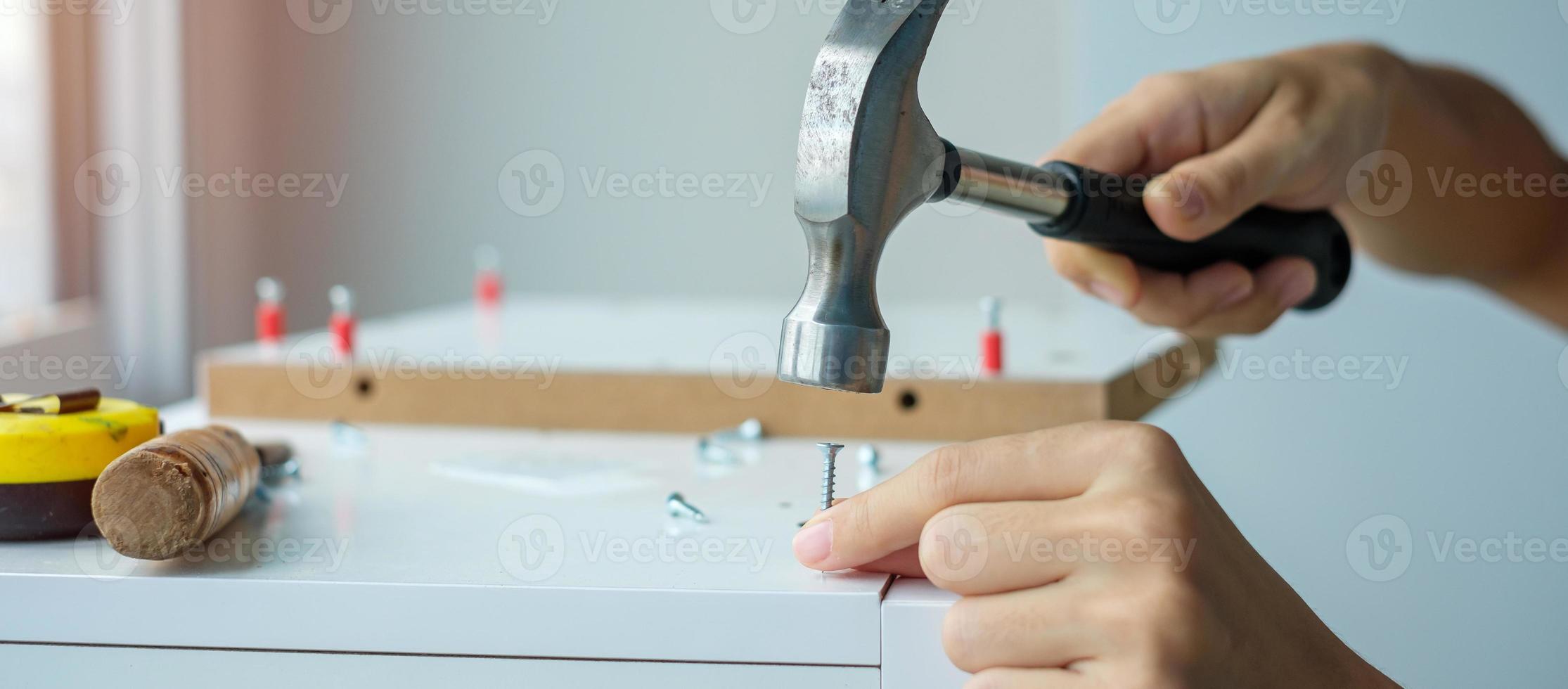 hombre usando un martillo clavando un clavo en tablas de madera, ensamblando o reparando muebles en casa. conceptos de bricolaje, renovación, reparación y desarrollo de viviendas o apartamentos foto