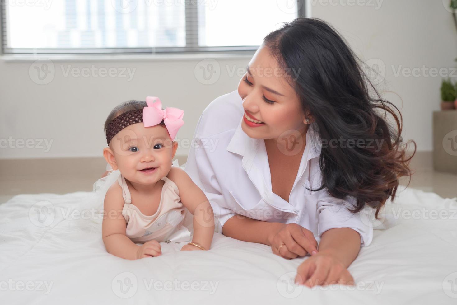 joven madre asiática y su bebé tirados en el suelo foto