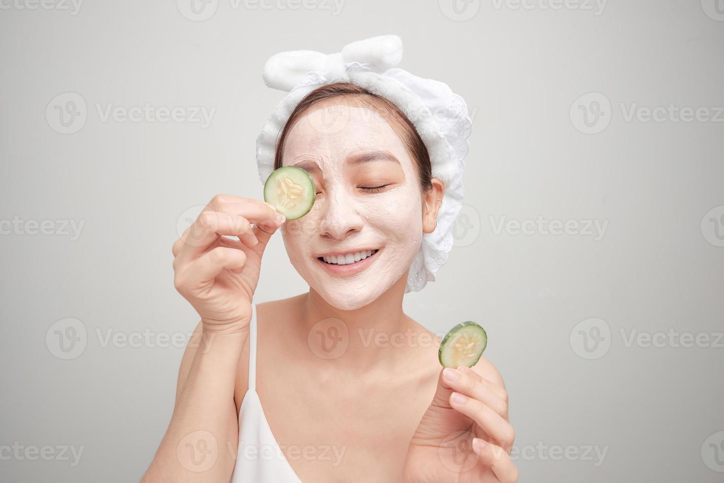 Attractive young woman covering her eyes with cucumbers on a blue background. Clay mask. photo