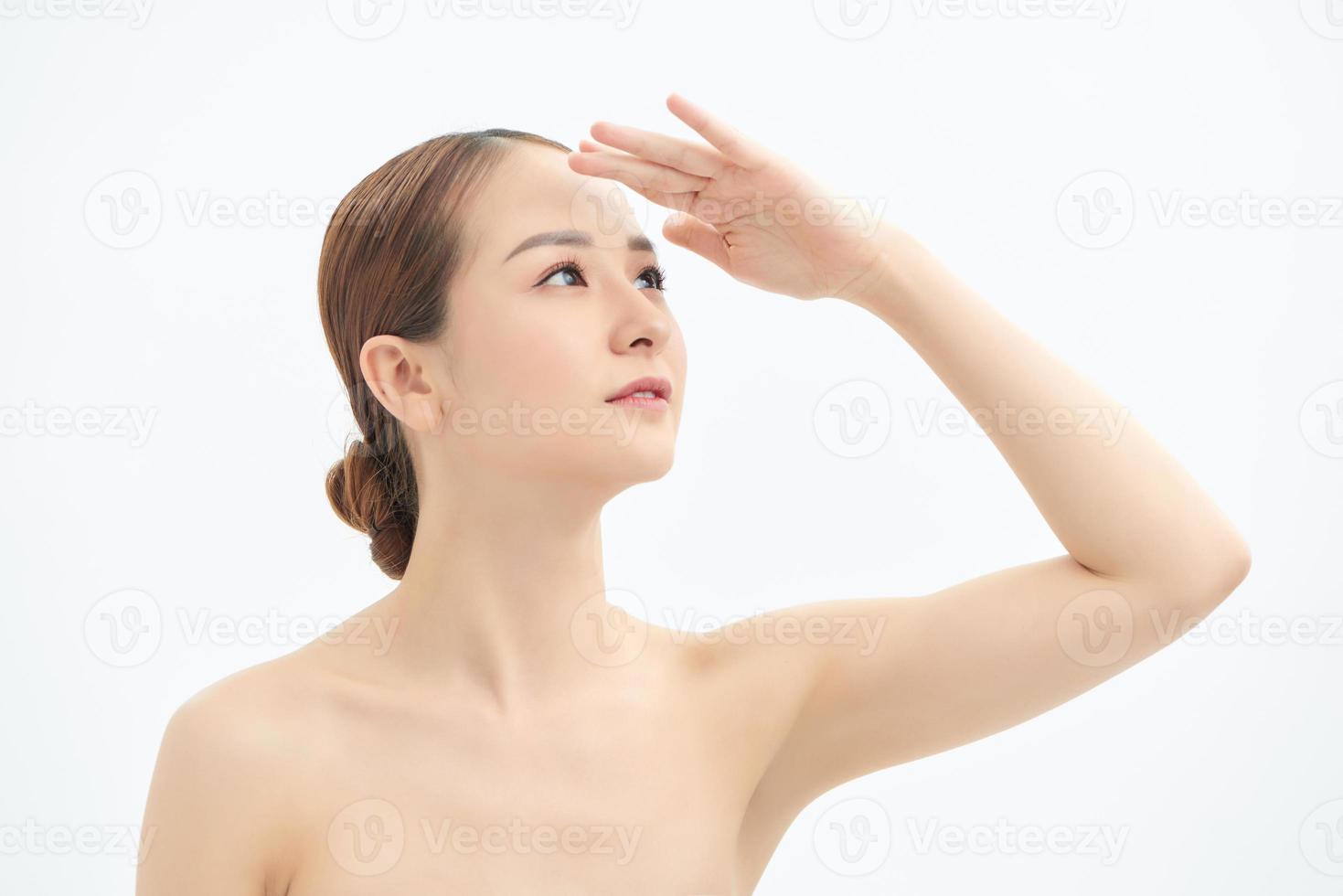 Young Asian woman looking up and showing hand to cover the light. photo