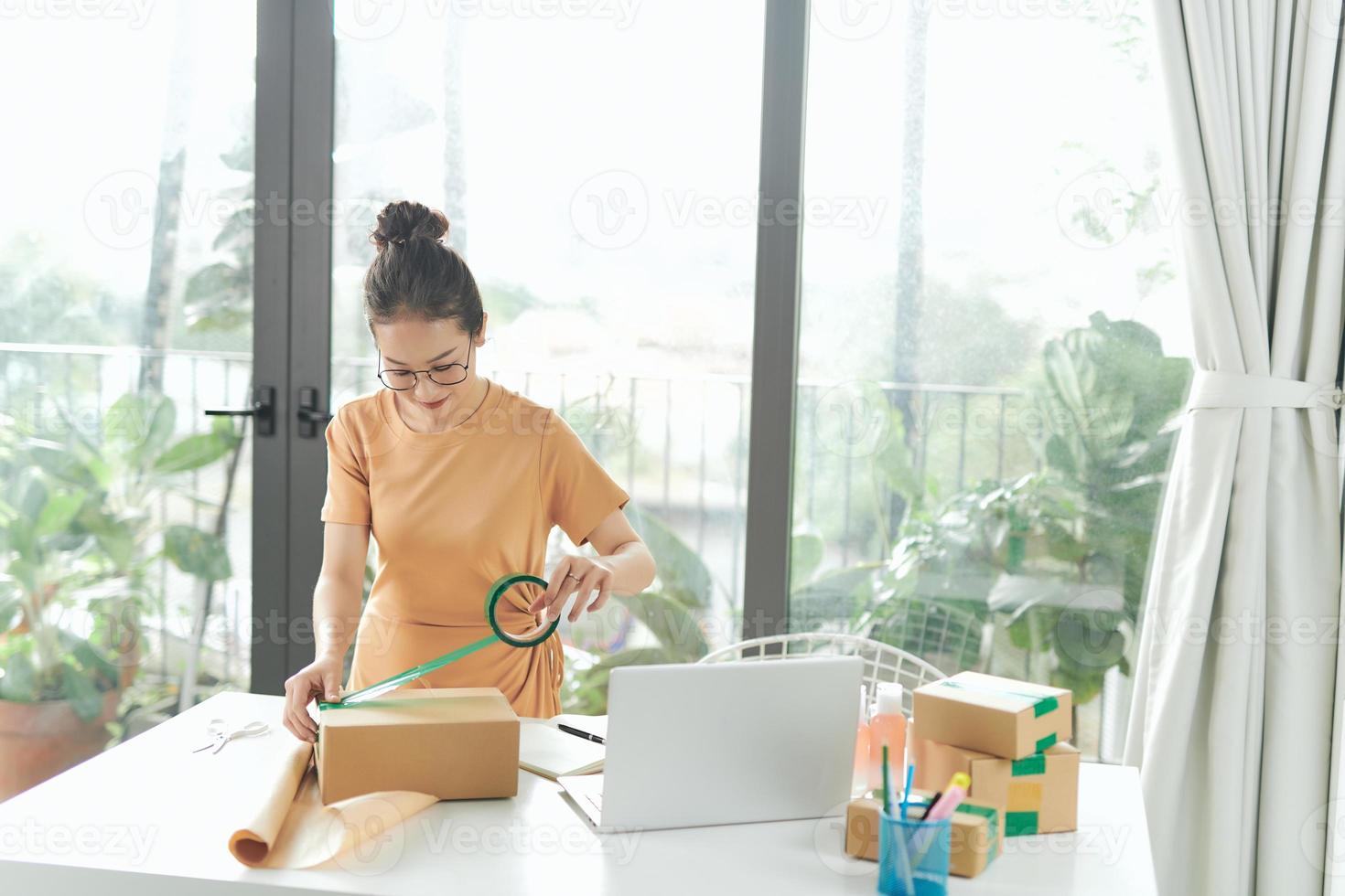 propietario de una pequeña empresa que trabaja en casa, mujeres que sellan cajas de cartón con cinta adhesiva, foto