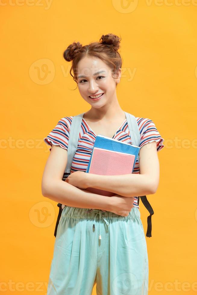 Happy student girl, isolated on yellow photo