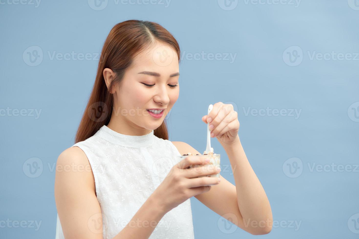 mujer joven atractiva disfrutando de una comida saludable comiendo una mezcla de yogur y muesli con fruta foto