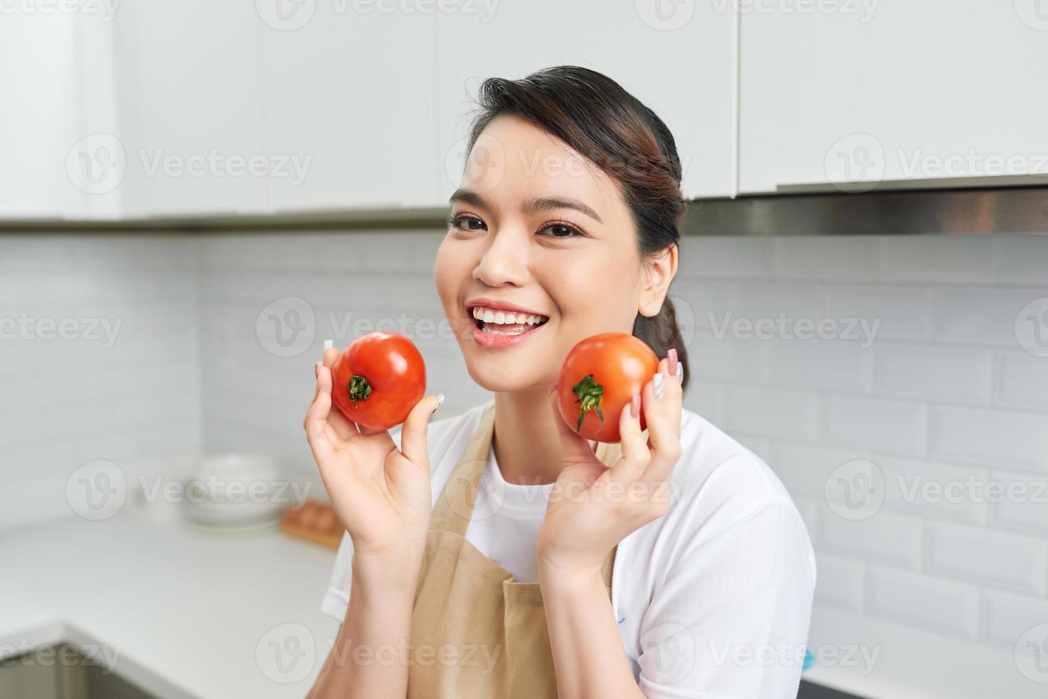 Portrait of her she nice attractive lovely confident cheerful cheery girl holding in hands tomato cooking everyday domestic meal lunch luncheon veg in modern light white interior kitchen photo