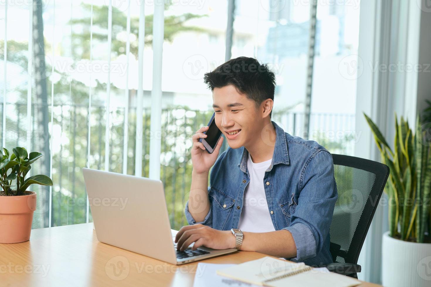 man talking on mobile phone, working from home. Portrait of pensive asian businessman using laptop computer, planning project, communication in modern office photo