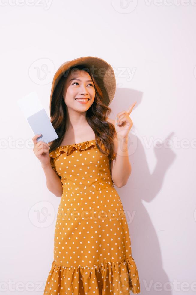 Cheerful young woman standing isolated over pink background, showing passport with flight tickets photo