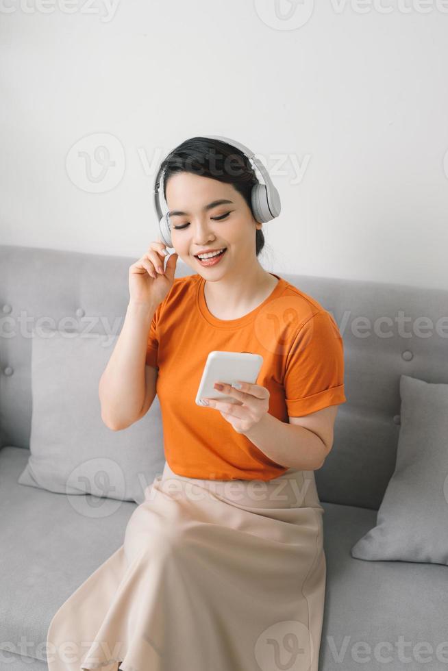 Serene young woman resting on sofa wearing casual home clothes wireless headphones enjoy weekend free time photo