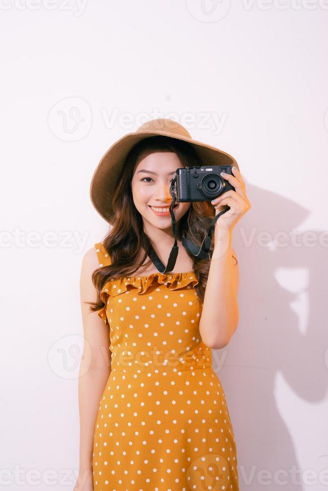 retrato de una joven sonriente con sombrero con una cámara posando aislada en un fondo pastel foto