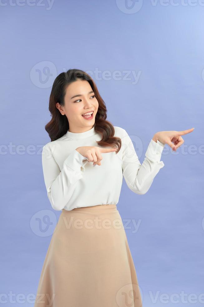 Attractive brunette girl isolated over purple background pointing at a copy space photo