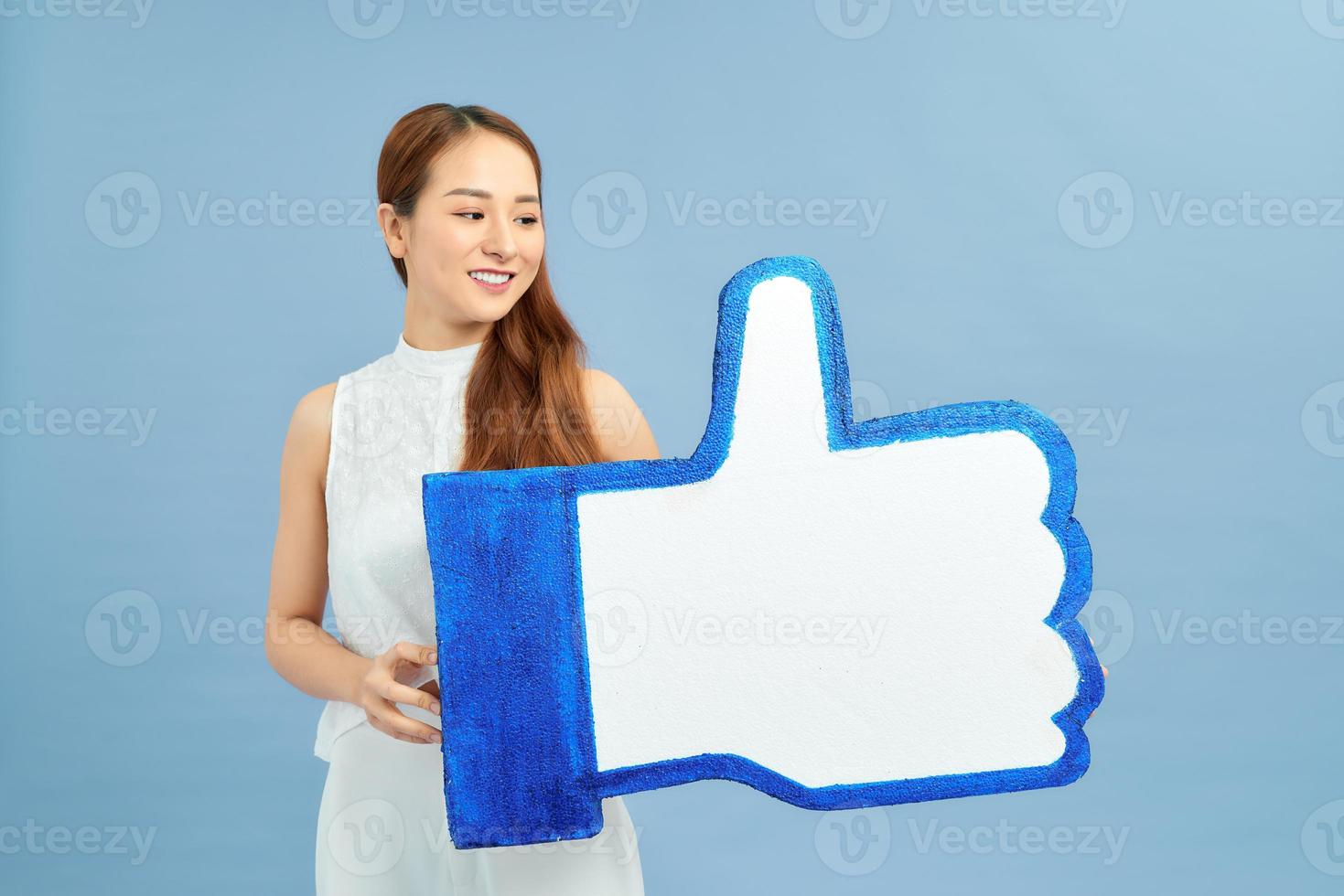 Portrait of attractive smiling girl holding blue thumb up icon photo