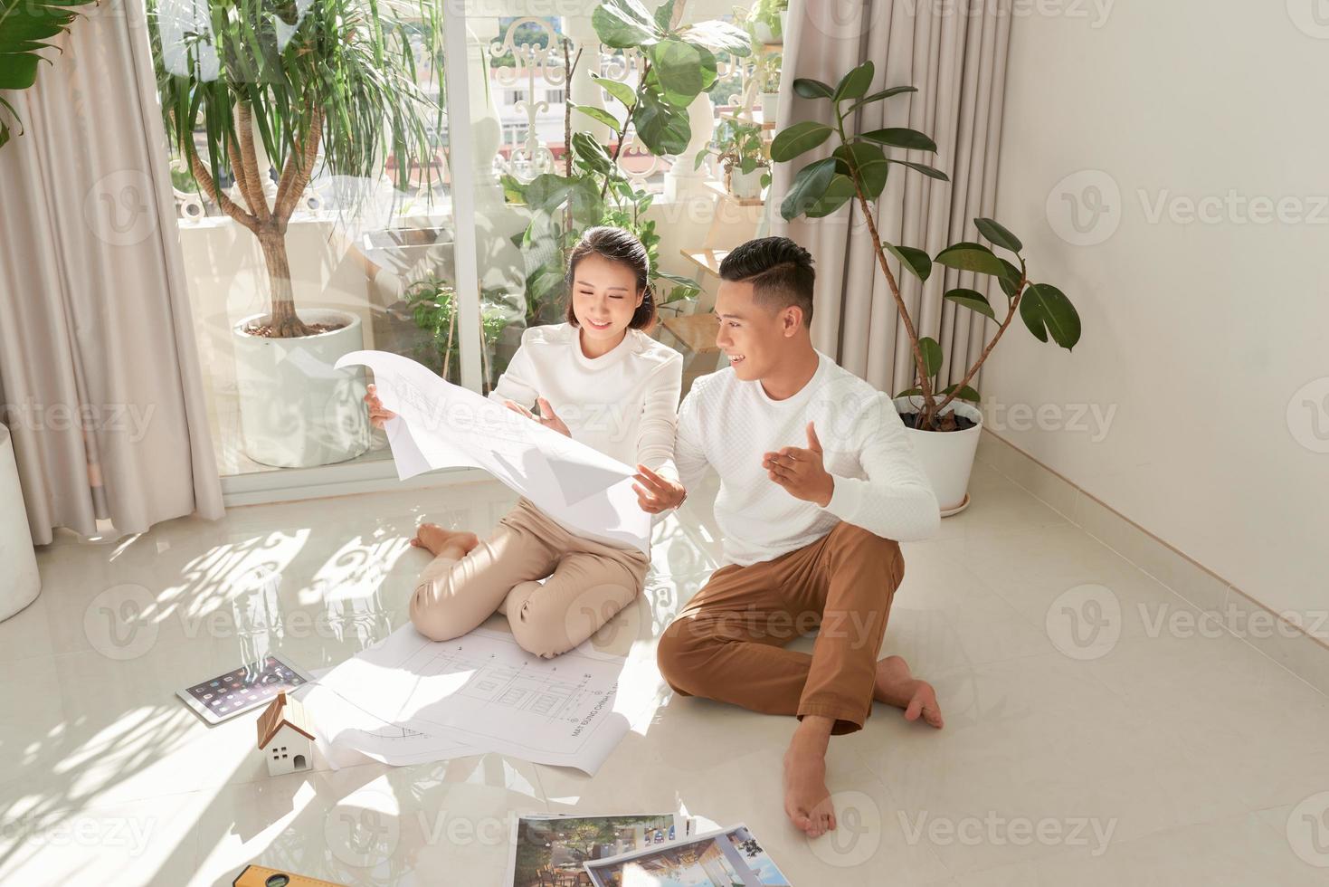 Young couple sitting on floor with apartment plan photo