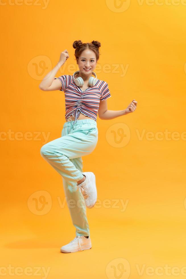Lovely asian girl standing on one leg. Full length view of attractive stylish japanese woman jumping on purple background. photo