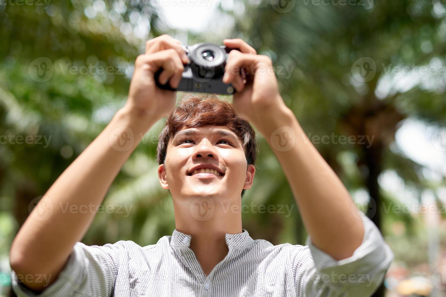 Young attractive man, a photographer, taking photographs in an urban area photo