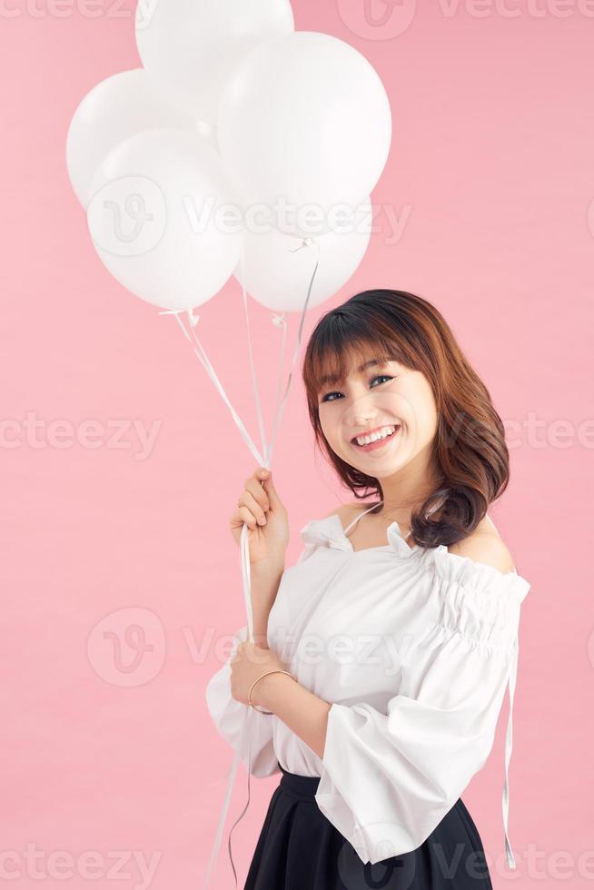 Cheerful young woman with balloons standing and laughing photo