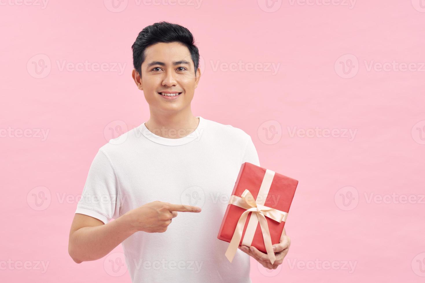 Smiling adult men casual dressed having red present in hand on pink background, with text space photo