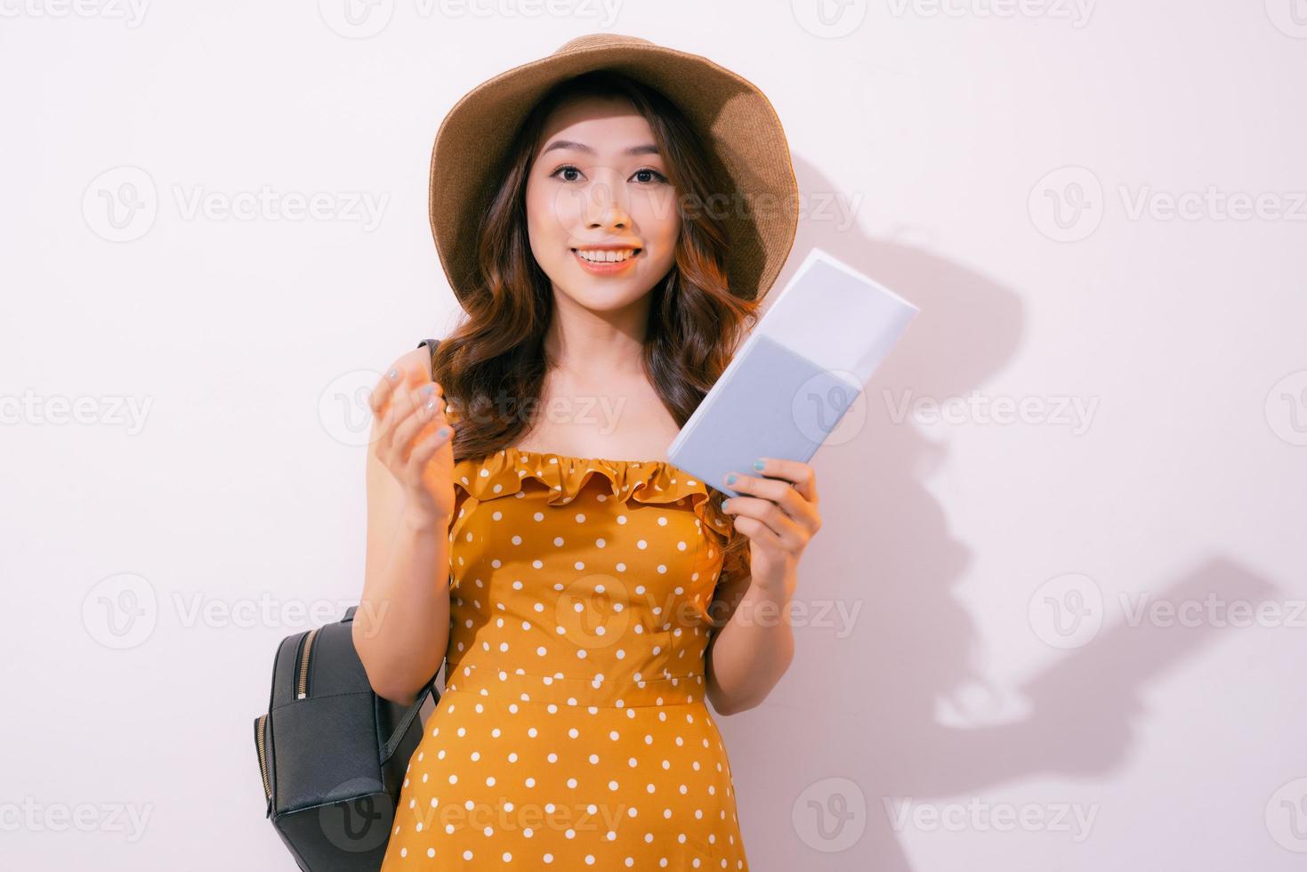 Cheerful young woman standing isolated over pink background, showing passport with flight tickets photo