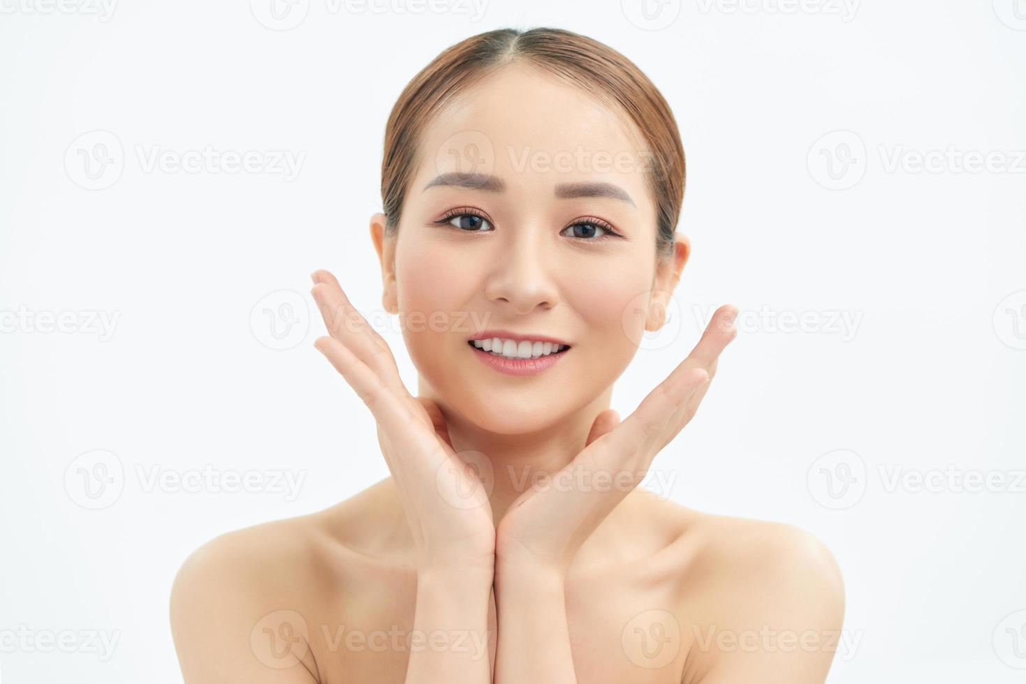 Beautiful young Asian woman with fresh clean skin that touches her face with both hands. Spa, cosmetology and beauty. photo