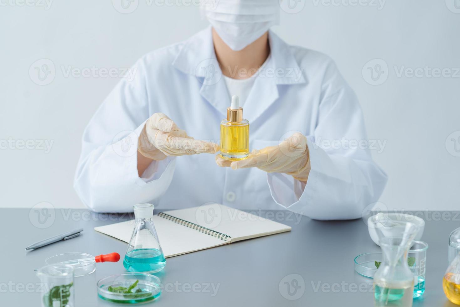 Female dermatologist holding bottle of skin care product at table, closeup photo