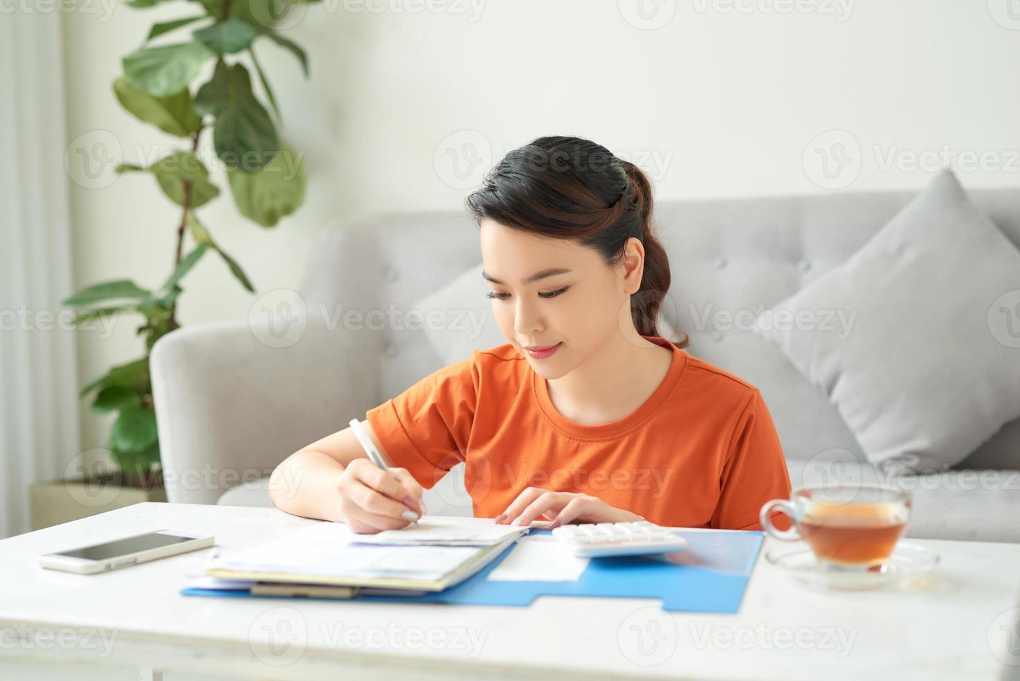 A young woman is sitting in living room and is looking at her receipts at home photo