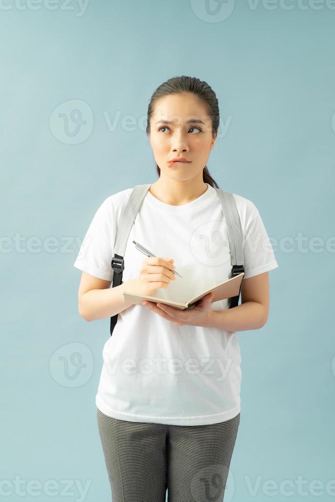 Puzzled indecisive troublesome college student frowns face in displeasure, diary in hands, thinks about writing new essay photo