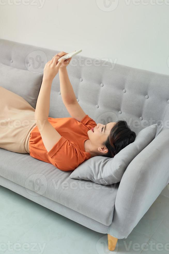 Happy woman using mobile phone on sofa photo