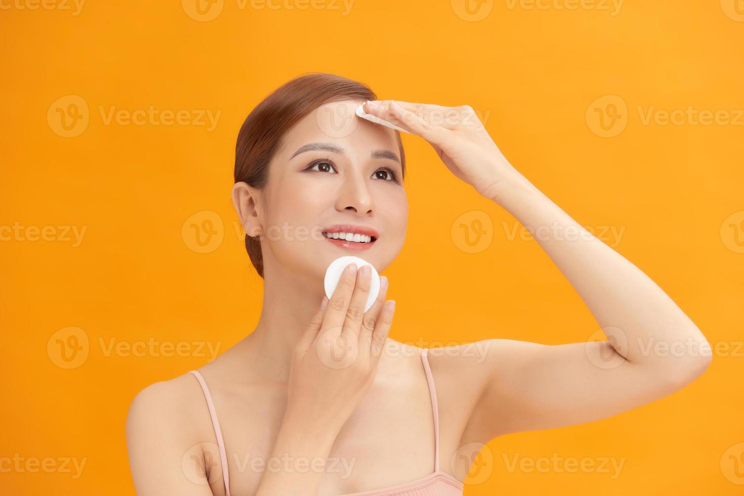 Woman using cotton pad. Happy smiling beautiful young woman cleaning skin by cotton pad. photo