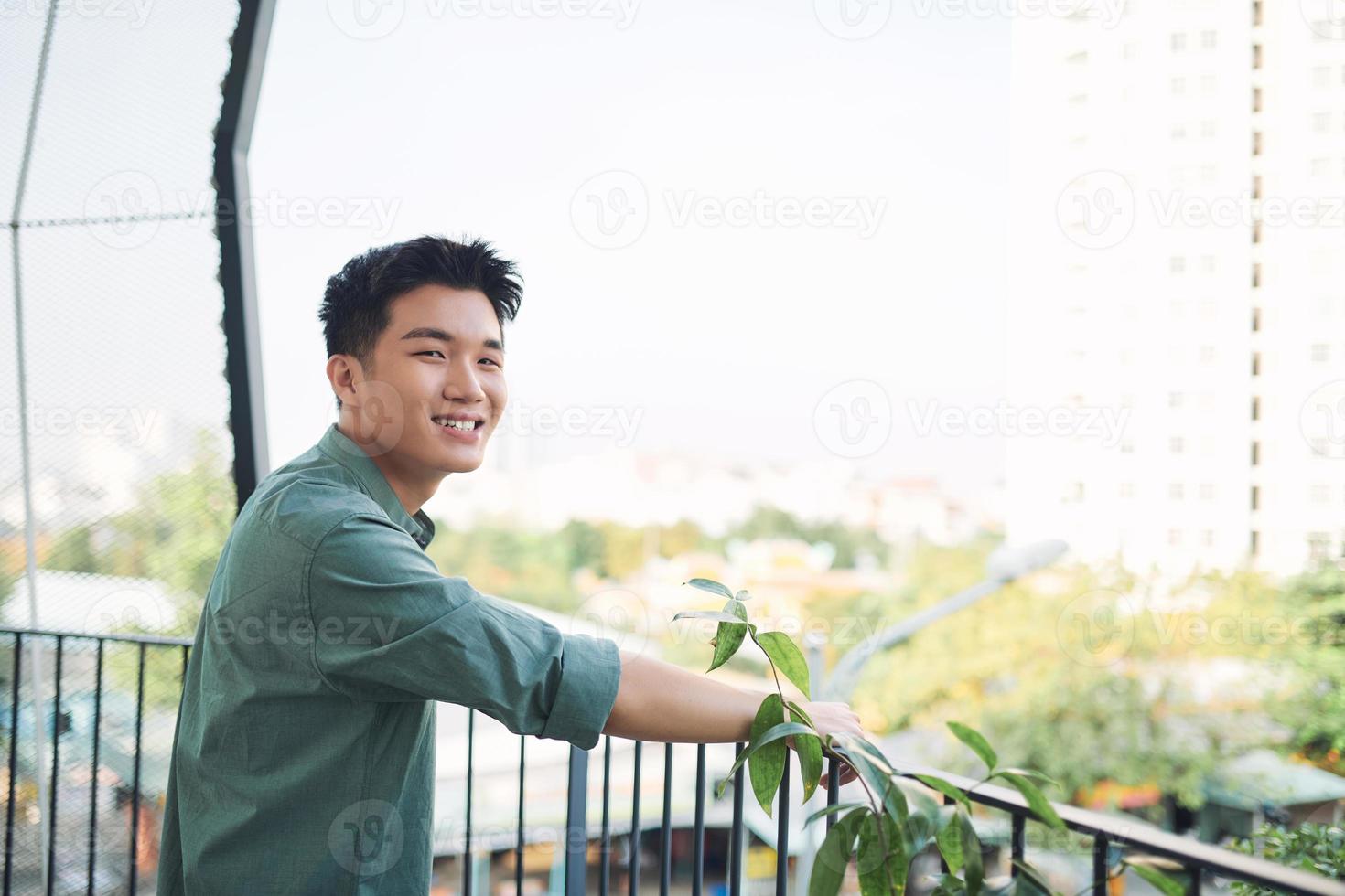 joven asiático esperando y apoyado en el pasamanos foto