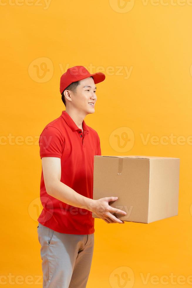 Cheerful delivery man. Happy young courier holding a cardboard box and smiling while standing against white background photo