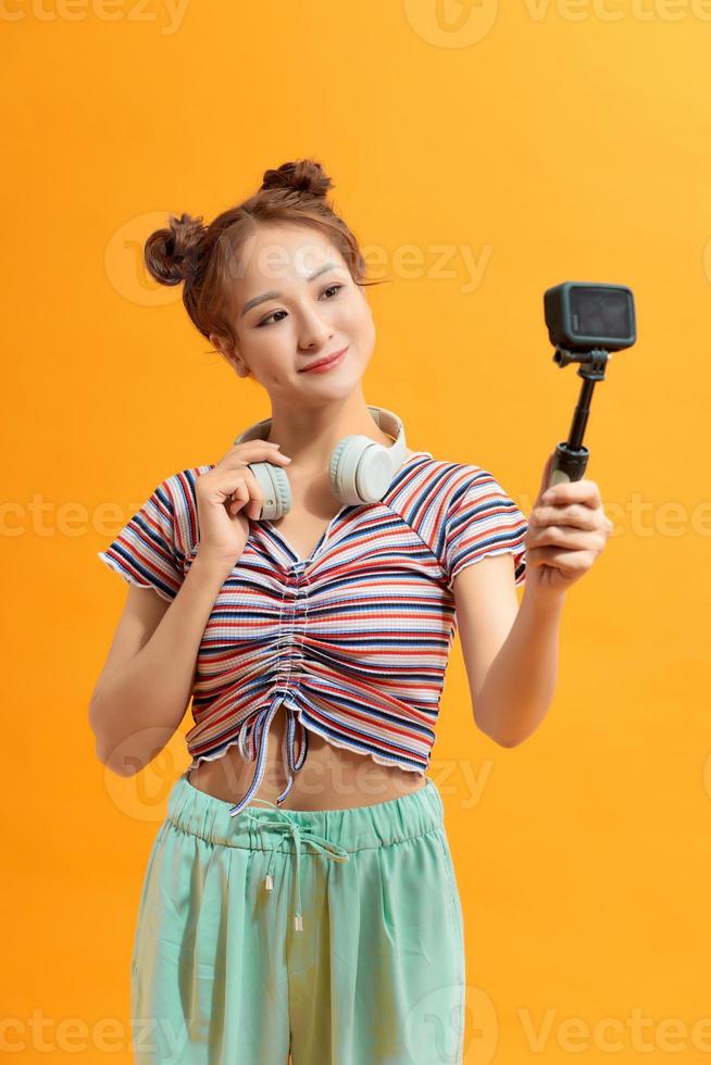 Pretty young woman smiling holding action camera photo