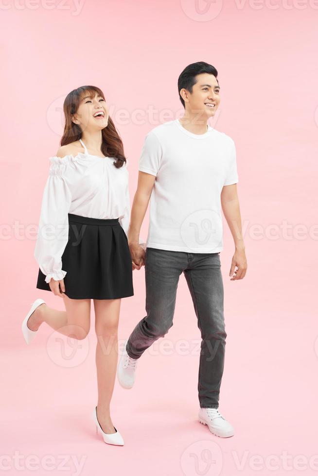 Studio shot of beautiful young couple walking together and holding hands photo
