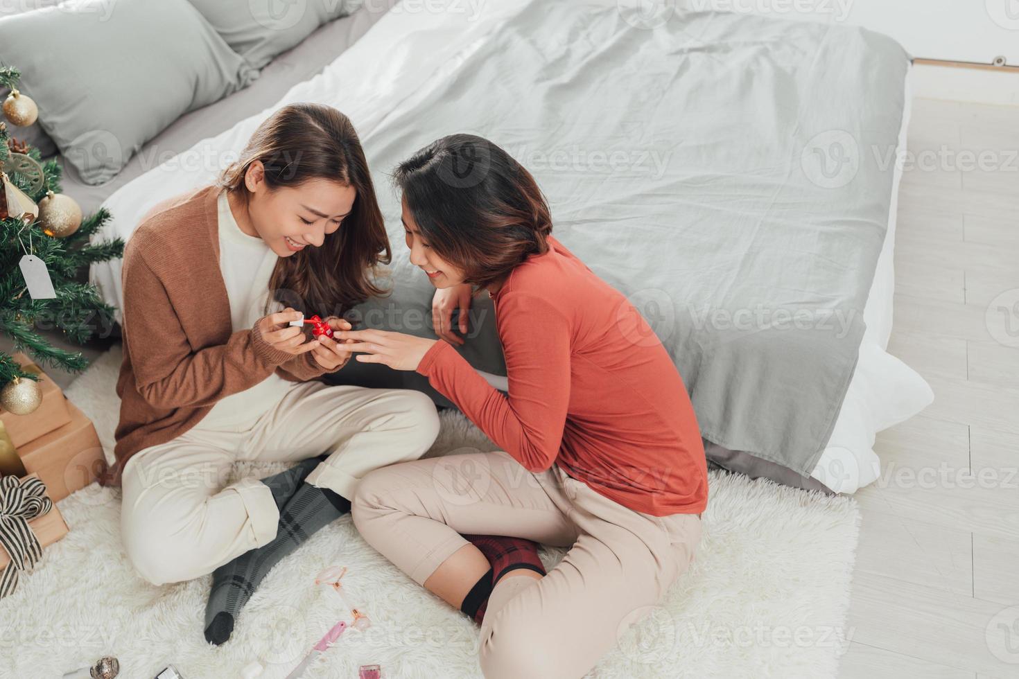 dos maravillosas y hermosas mujeres asiáticas jóvenes pintan uñas yendo a pedicuras, una de ellas sopla en las uñas foto