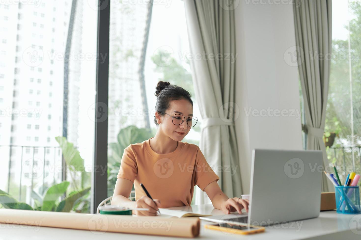 woman checking purchase order in laptop and write in the delivery on package box photo