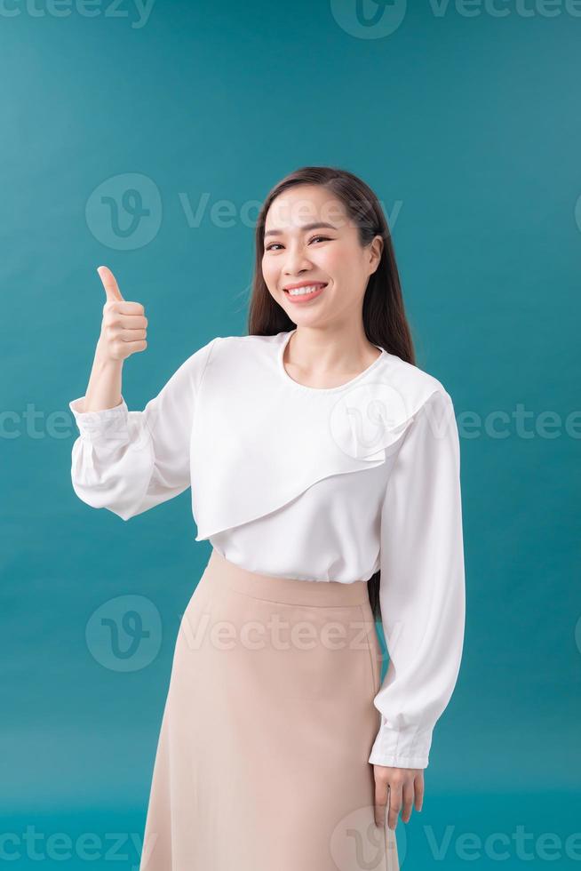 Smiling pretty young woman showing thumb up isolated on the blue background photo
